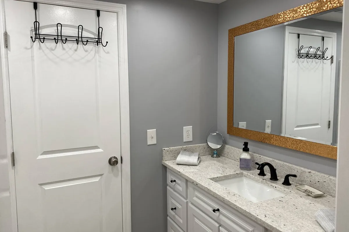This image depicts a modern vanity area with a mirror, sleek sink, granite countertop, and a towel rack. Bright morning light enhances the feeling of freshness and cleanliness, with the countertop referencing the granite details highlighted in the section.