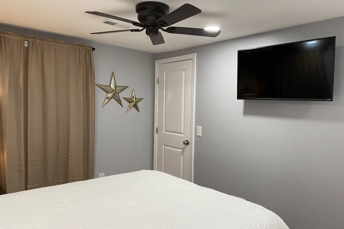A comfortable bedroom with a plush bed, a smart TV, and playful star decorations. The setting is perfect for relaxing, watching shows, or reading before sleep, conveying the home’s focus on modern amenities and comfort.