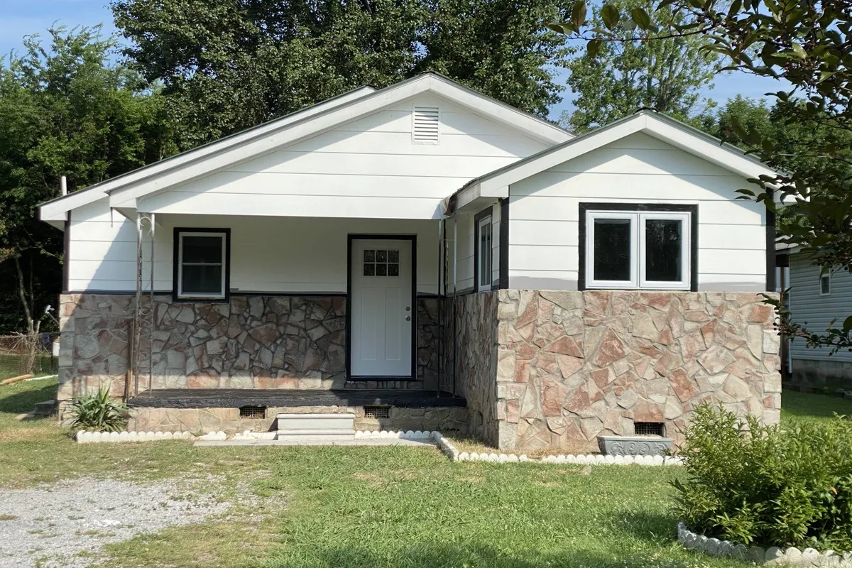A welcoming view of the home's front door with a charming stone facade and windows. The inviting exterior hints at a cozy, family-friendly environment. Space around the entryway offers plenty of room for pets and children to play or stretch their legs before heading to nearby attractions.